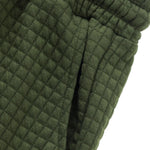 Close-up detail of olive green textured drawstring shorts with elastic waistband and white rope tie.