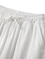 Close-up detail of white drawstring pants with elastic waistband and soft textured fabric.