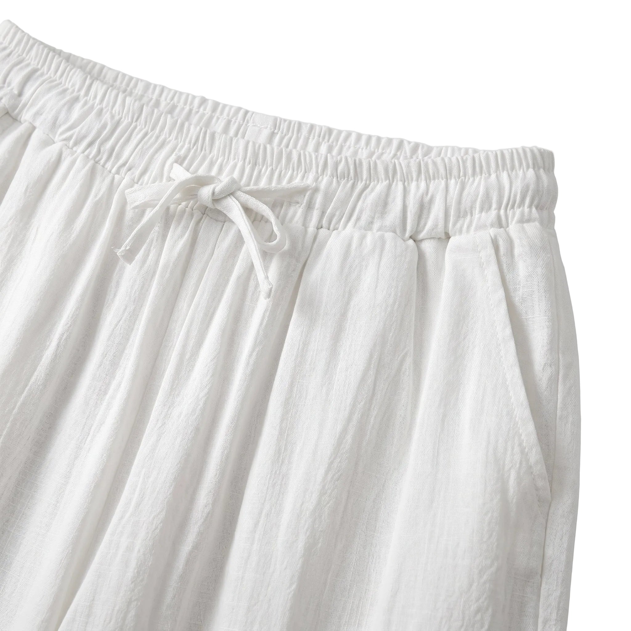 Close-up detail of white drawstring pants with elastic waistband and soft textured fabric.