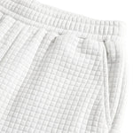 Close-up detail of white textured summer shorts with elastic waistband and drawstring tie.