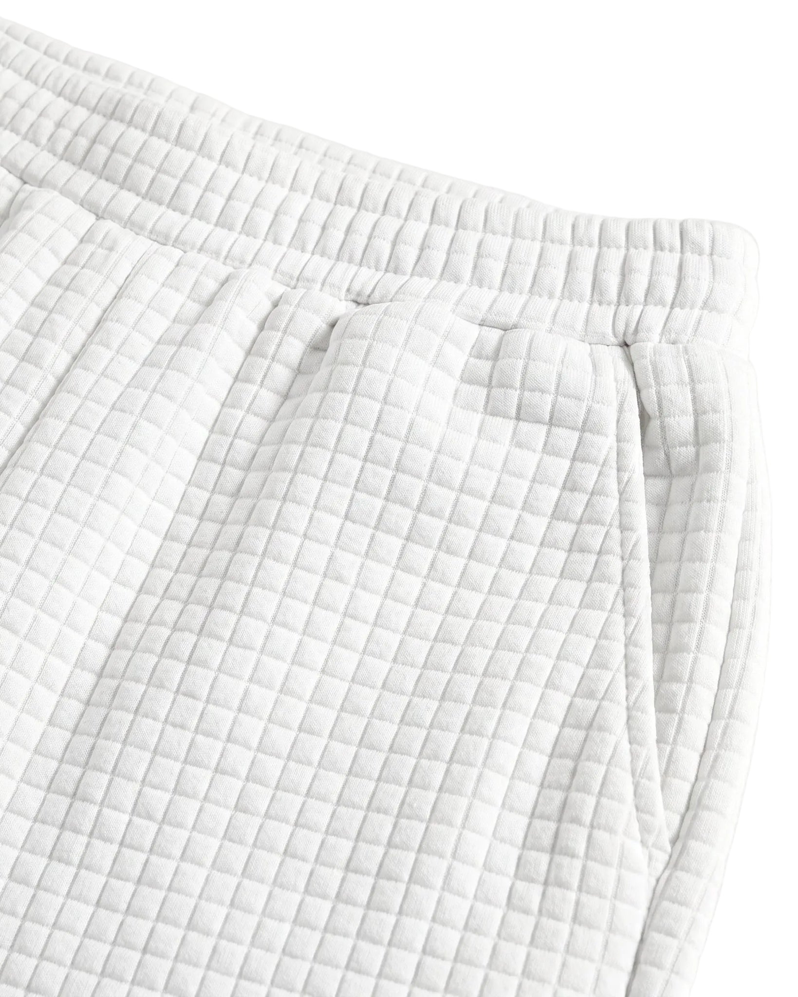 Close-up detail of white textured summer shorts with elastic waistband and drawstring tie.