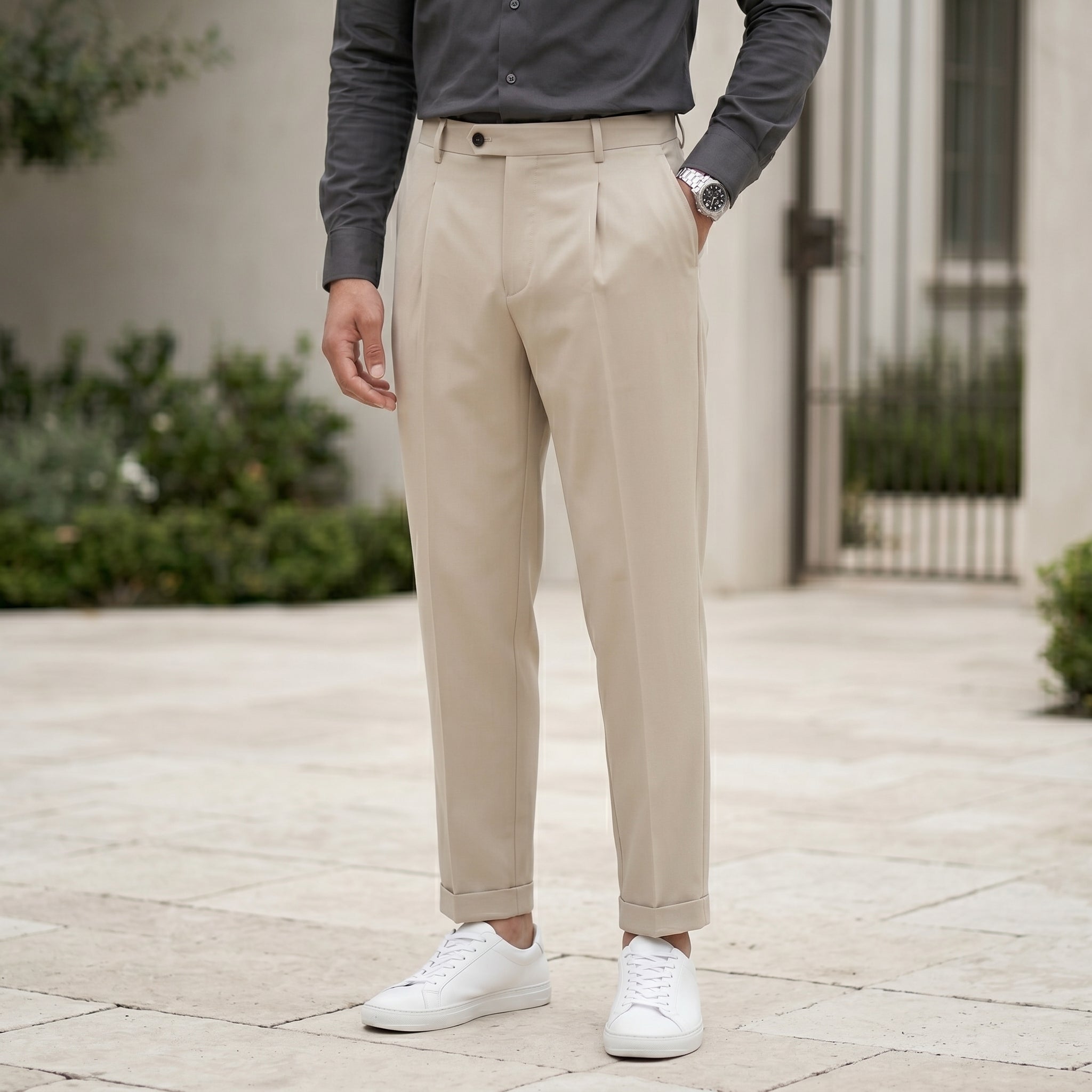 Close-up front view of male model wearing beige pleated casual pants with a relaxed tapered fit.