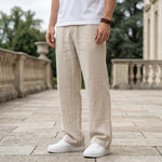 Close-up front view of male model wearing beige textured relaxed-fit pants with a straight-leg fit.