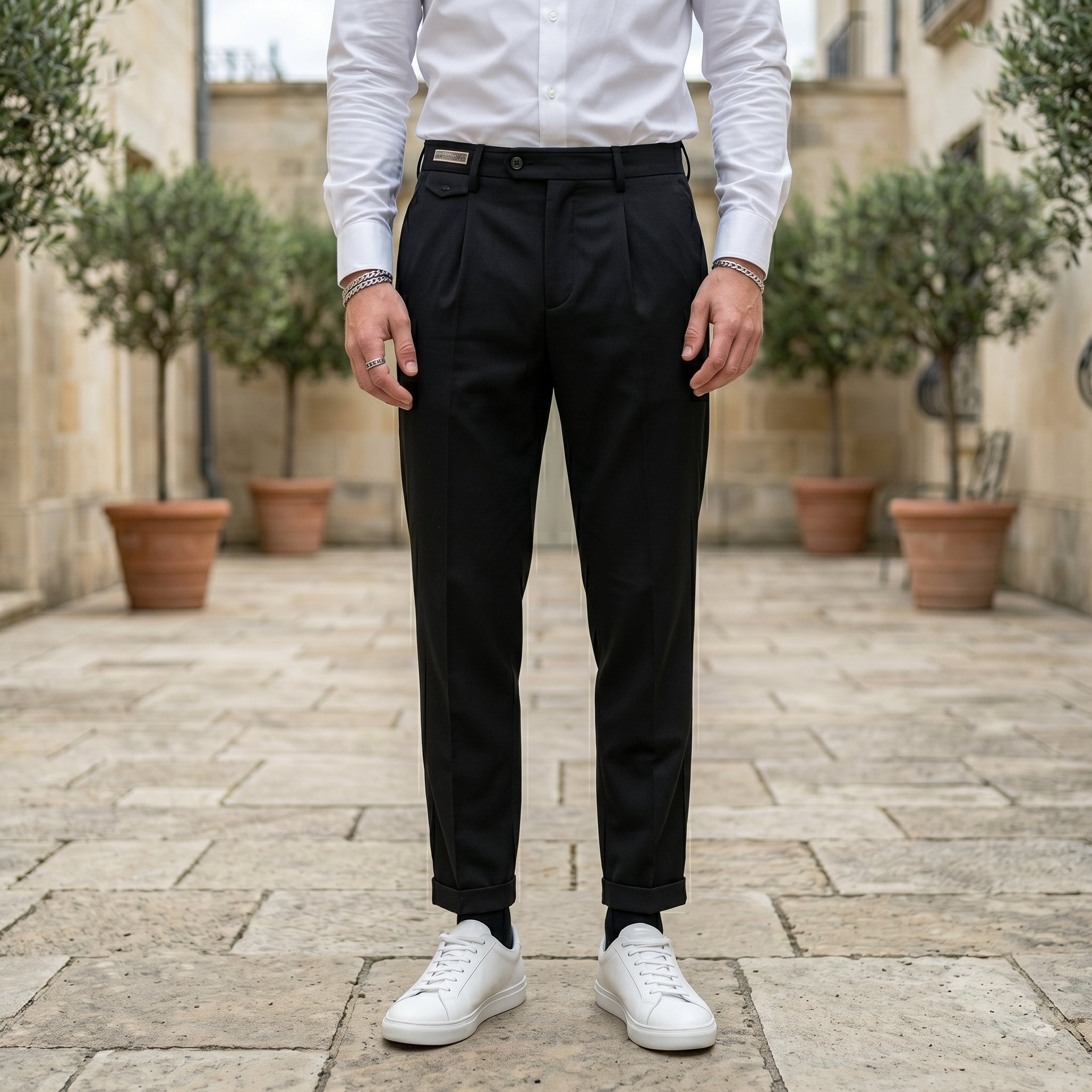 Close-up front view of male model wearing black pleated tailored pants with a relaxed straight-leg fit.