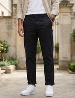 Close-up front view of male model wearing black relaxed-fit casual pants with a beige overshirt.