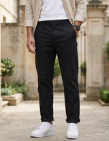 Close-up front view of male model wearing black relaxed-fit casual pants with a beige overshirt.