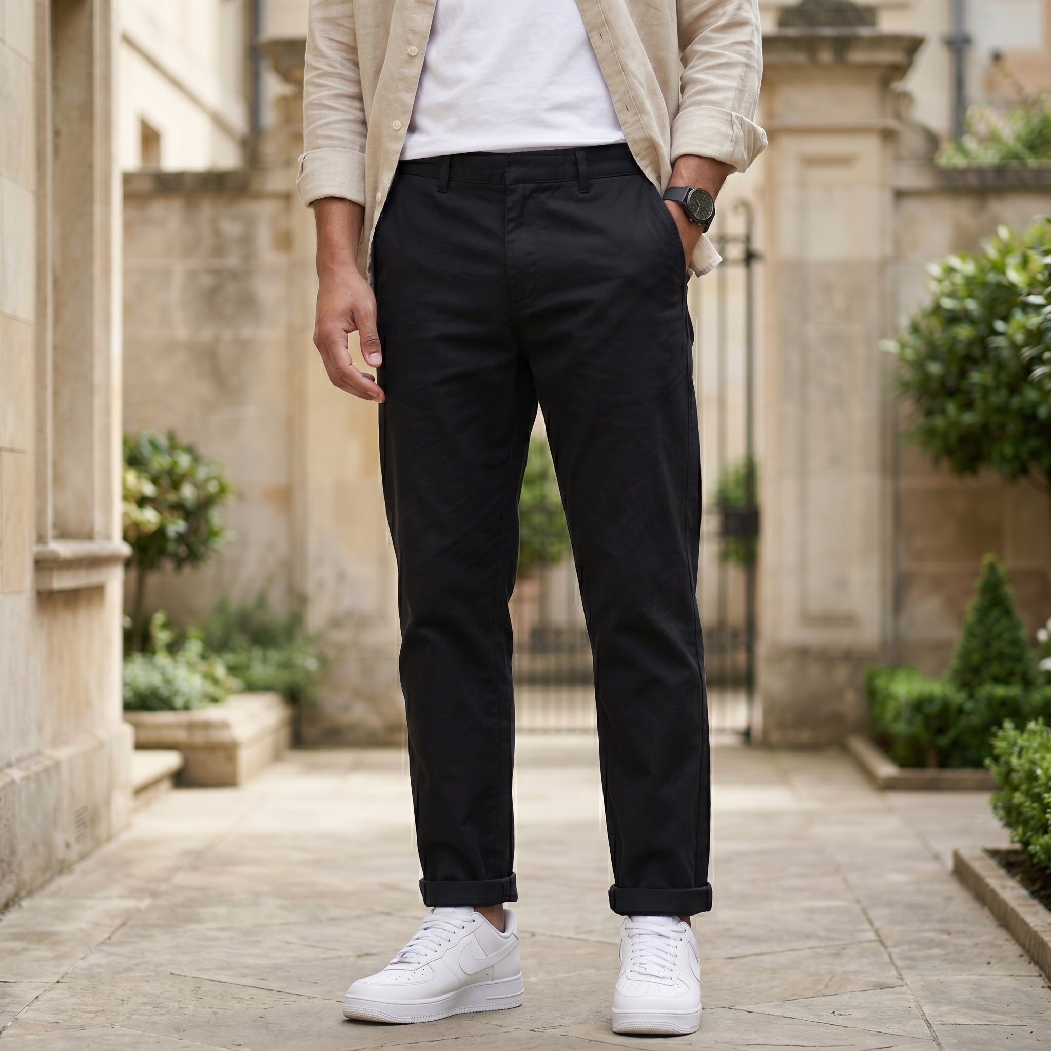Close-up front view of male model wearing black relaxed-fit casual pants with a beige overshirt.