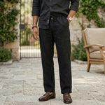 Close-up front view of male model wearing black relaxed-fit casual pants with a black long-sleeve shirt.