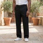 Close-up front view of male model wearing black relaxed-fit casual pants with a white short-sleeve shirt.