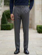 Close-up front view of male model wearing dark gray pleated tailored pants with a slim straight-leg fit.