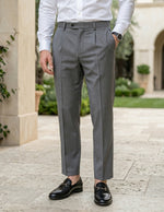 Close-up front view of male model wearing gray pleated tailored pants with a slim straight-leg fit.