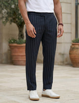 Close-up front view of male model wearing navy pinstripe relaxed-fit pants with straight legs.