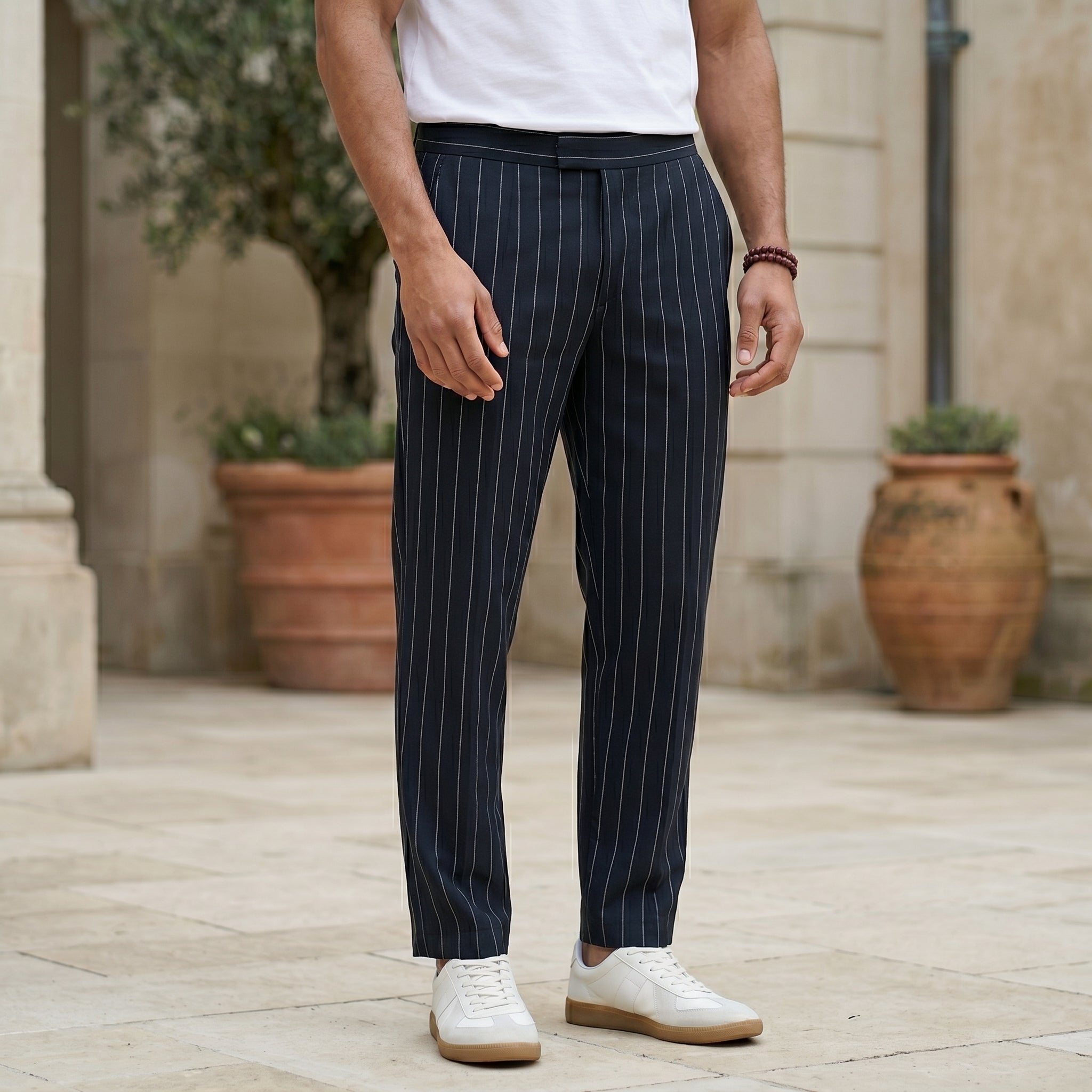 Close-up front view of male model wearing navy pinstripe relaxed-fit pants with straight legs.