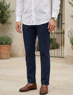 Close-up front view of male model wearing navy tailored pants with a slim straight-leg fit.