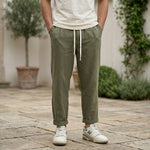 Close-up front view of male model wearing olive green drawstring jogger pants with a tapered fit.