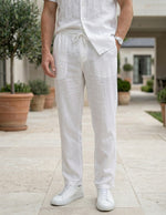 Close-up front view of male model wearing white drawstring relaxed-fit pants with a white short-sleeve shirt.