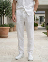 Close-up front view of male model wearing white drawstring relaxed-fit pants with a white short-sleeve shirt.