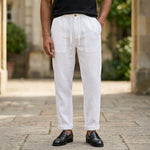 Close-up front view of male model wearing white relaxed-fit pants with a black short-sleeve polo shirt.