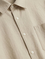 Close-up of a beige button-up shirt with a pocket.