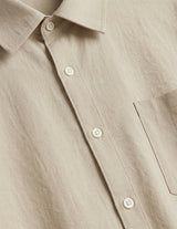 Close-up of a beige button-up shirt with a pocket.