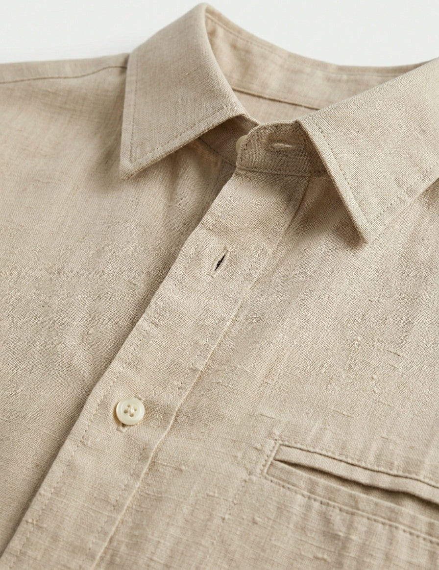 Close-up of a beige shirt with a collar and button detail on a light background