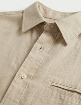 Close-up of a beige shirt with a collar and button detail on a light background