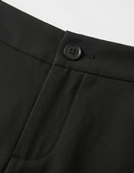 Close-up of a black button on a black garment against a light gray background