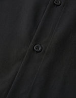 Close-up of a black buttoned shirt with a focus on texture and buttons.