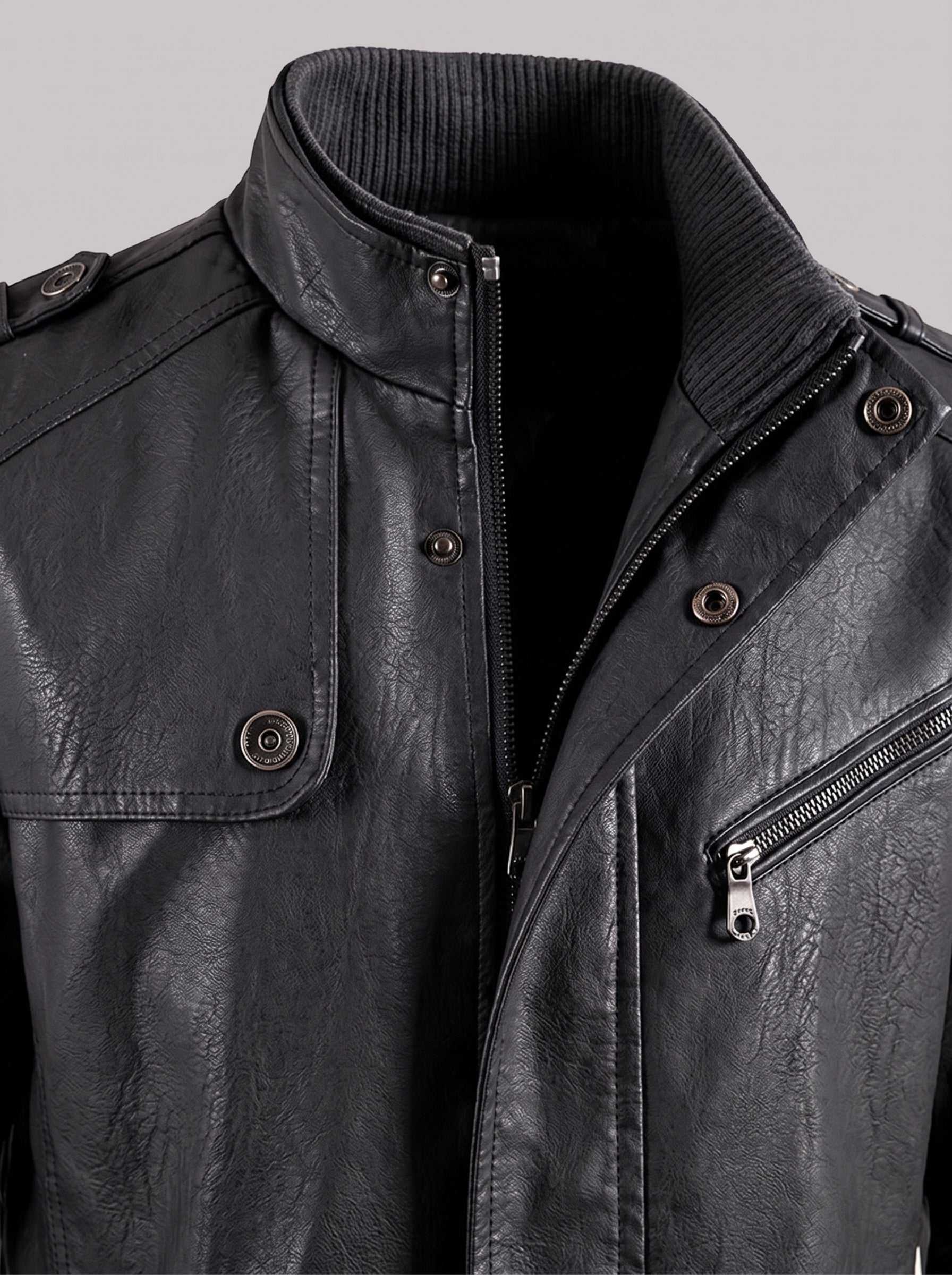 Close-up of a black faux leather jacket with a ribbed knit collar, front zipper, snap buttons, and a zippered chest pocket, shown against a light gray background.