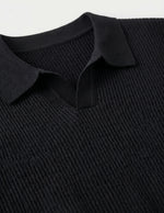 Close-up of a black ribbed sweater with a collar on a light gray background