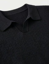 Close-up of a black ribbed sweater with a collar on a light gray background