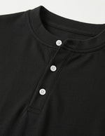 Close-up of a black shirt with button details on a light gray background