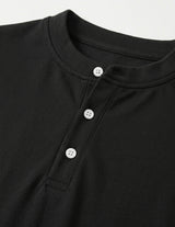 Close-up of a black shirt with button details on a light gray background
