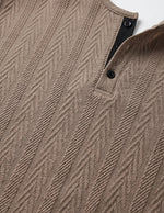 Close-up of a brown textured sweater with a patterned design.