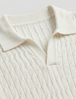 Close-up of a cream-colored ribbed sweater with a collar on a light gray background