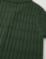 Close-up of a green ribbed sweater on a white background