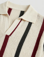Close-up of a knitted cardigan with red and black stripes on a light background