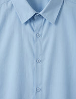 Close-up of a light blue shirt with collar and buttons
