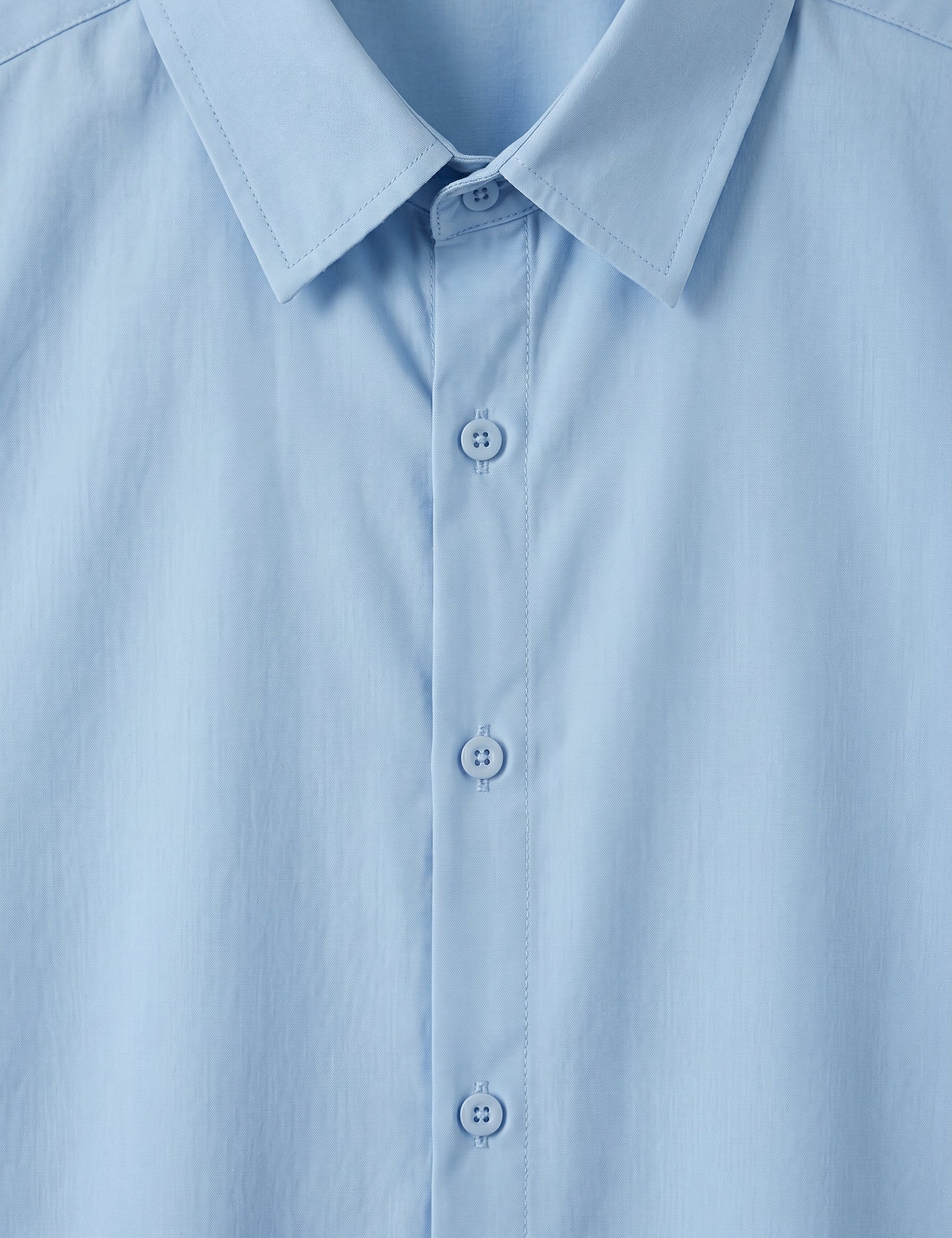 Close-up of a light blue shirt with collar and buttons