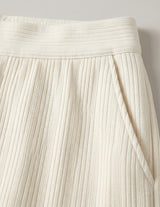 Close-up of a pleated cream skirt against a neutral background