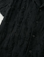 Close-up of a textured black garment with buttons