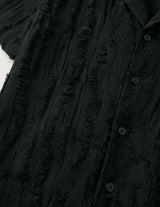 Close-up of a textured black garment with buttons