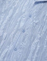 Close-up of a textured blue shirt with button details