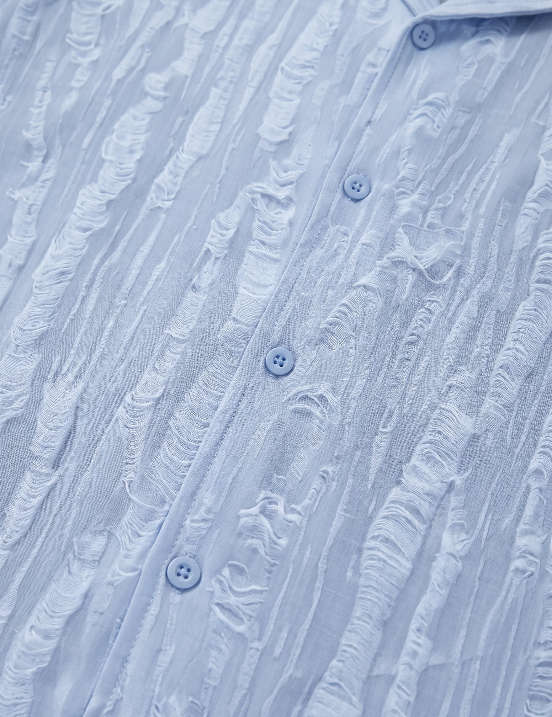 Close-up of a textured blue shirt with button details