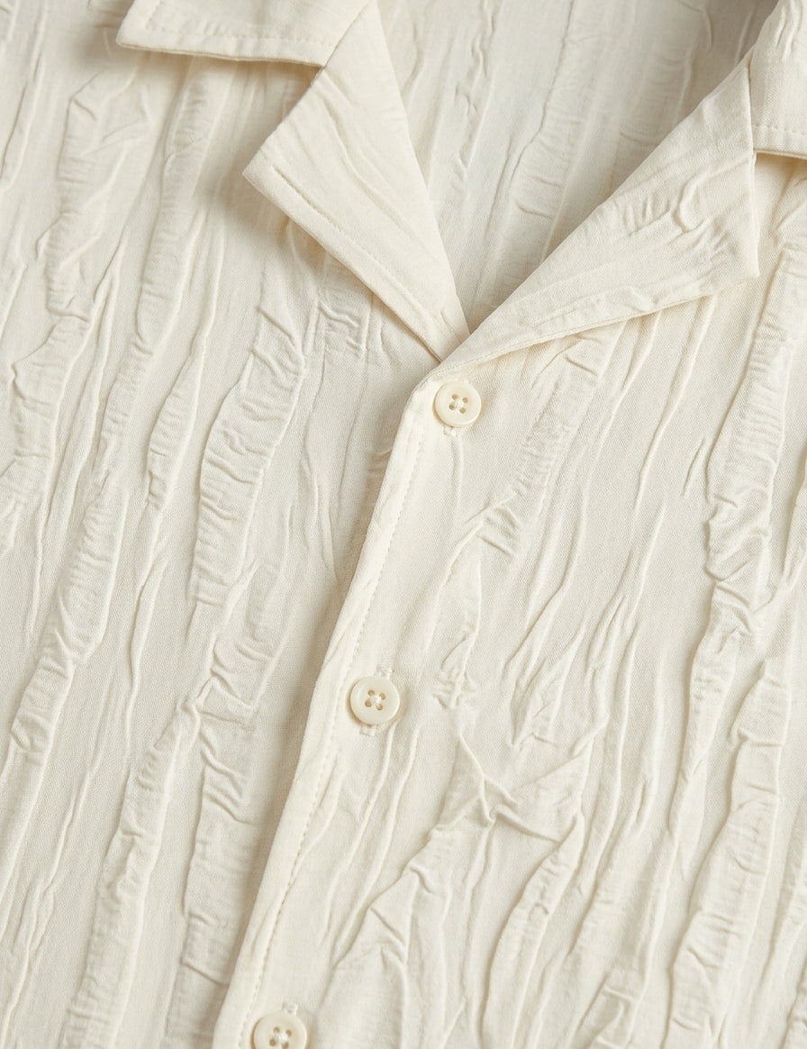 Close-up of a textured cream-colored shirt with buttons.