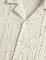 Close-up of a textured cream-colored shirt with buttons.