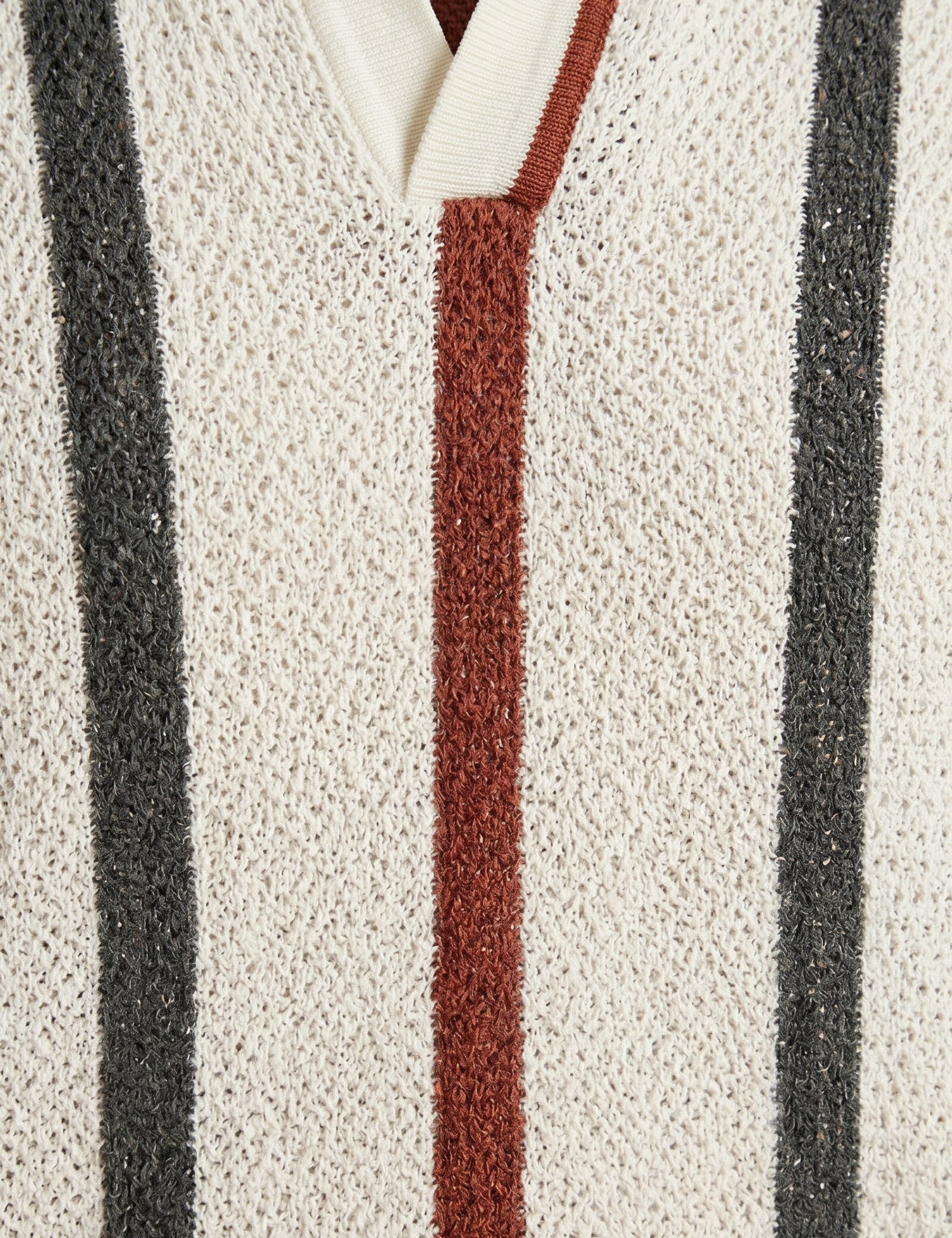 Close-up of a textured fabric with vertical stripes in black, red, and white.
