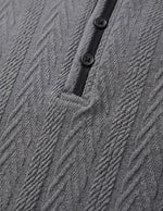 Close-up of a textured gray garment with buttons and a black strap.