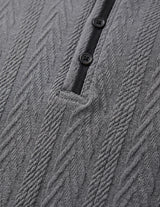 Close-up of a textured gray garment with buttons and a black strap.