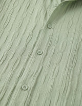 Close-up of a textured green shirt with button details